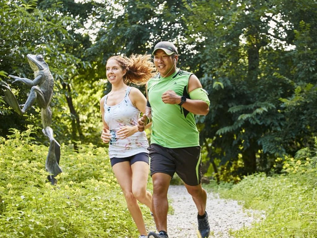 a man and a woman running on a trail in a park