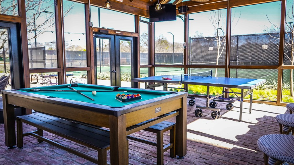 a games room with two pool tables and windows