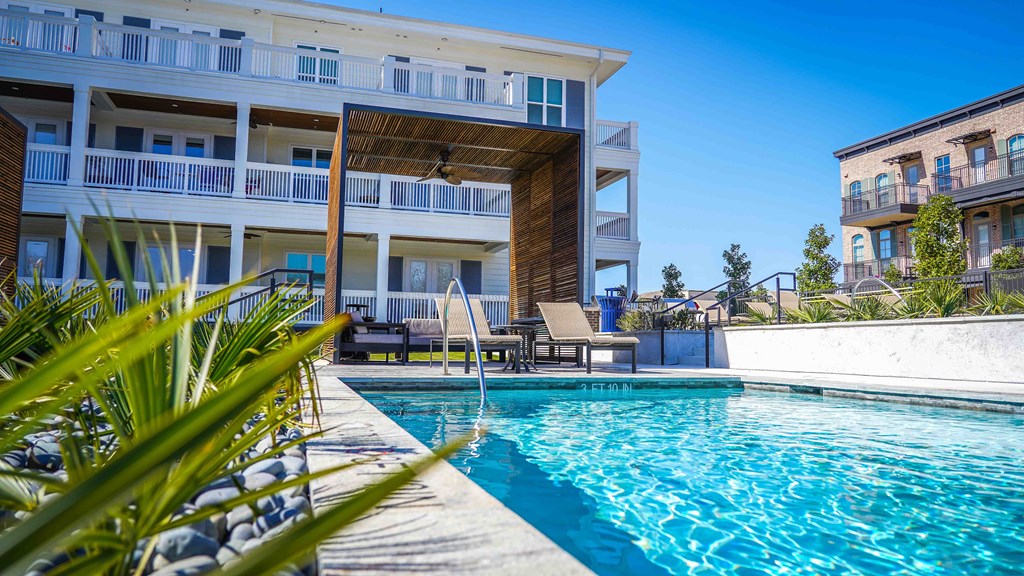 a large swimming pool with a house in the background