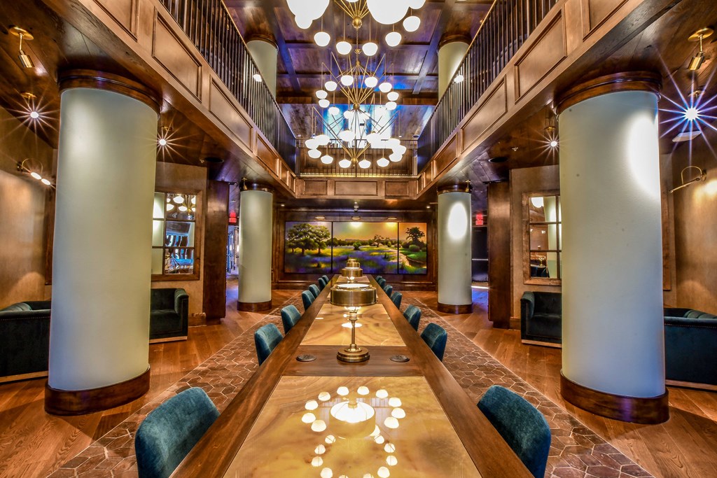 a long table in a lobby with chairs and a chandelier