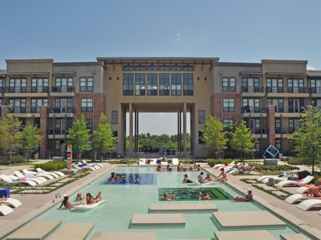 people swimming in a large pool in front of an apartment building