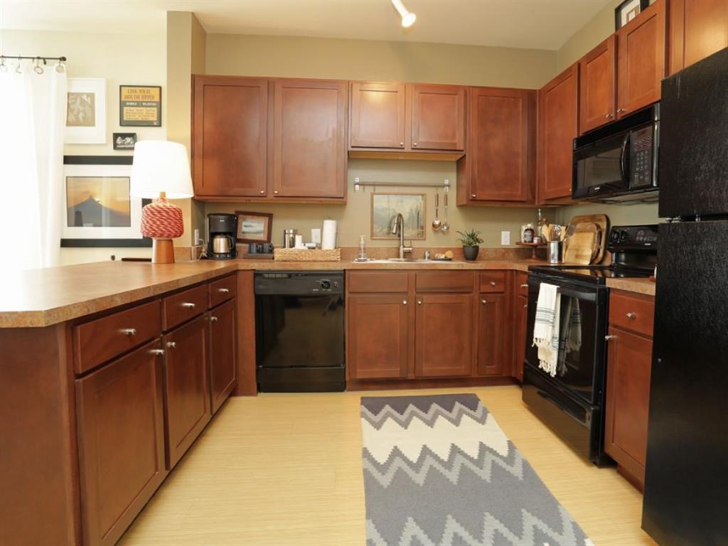 a large kitchen with wooden cabinets and black appliances