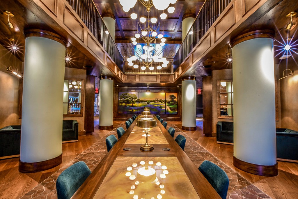 a long table in a lobby with chairs and a chandelier