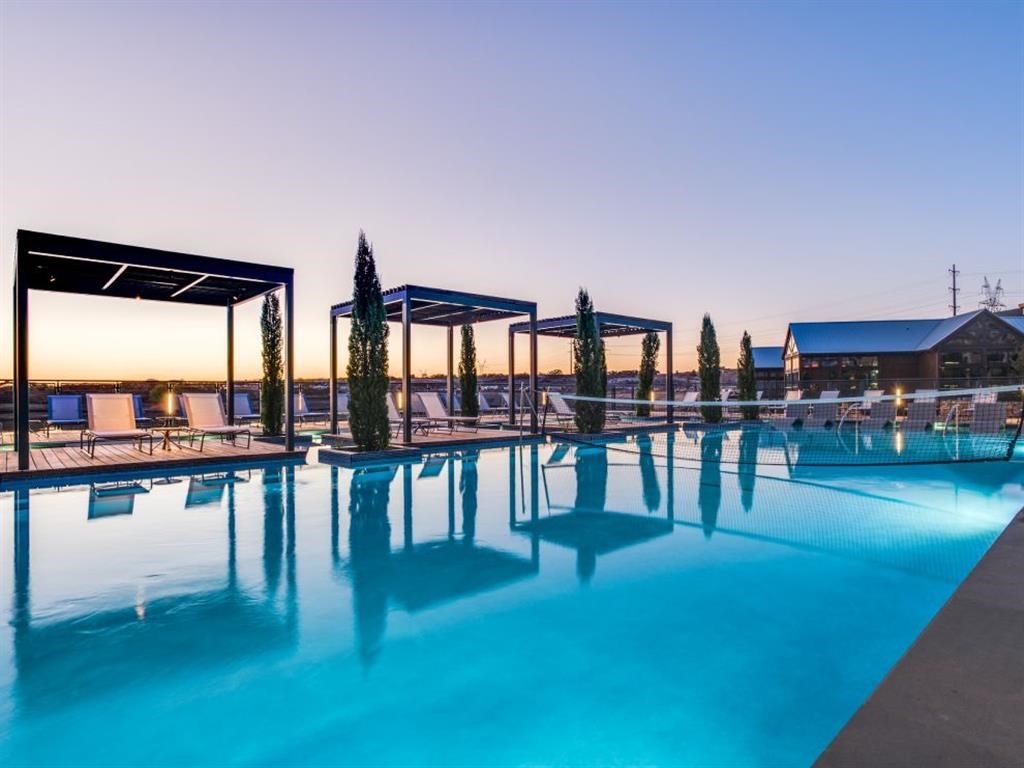 a swimming pool at dusk with trees and a building in the background