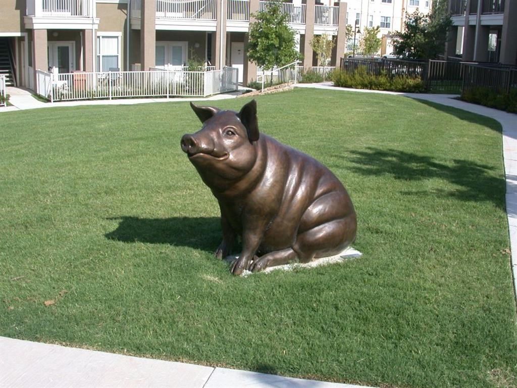 a statue of a brown pig sitting in the grass