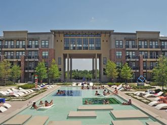 people swimming in a large pool in front of an apartment building