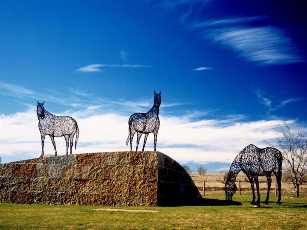 three giraffes standing on a rock in a field