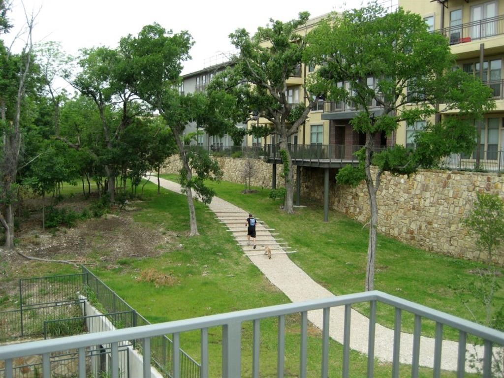 a person walking a dog down a path in front of an apartment building
