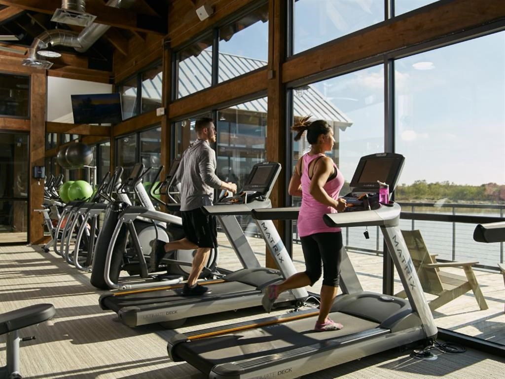 a man and a woman running on a treadmill in a gym