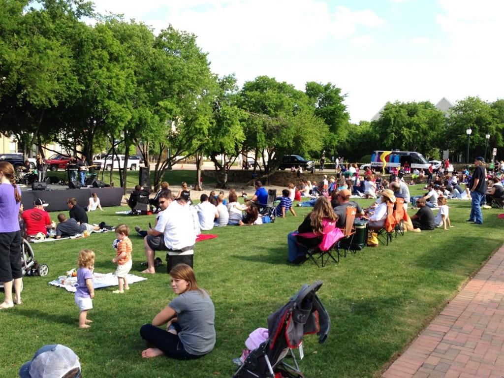 a crowd of people sitting on the grass in a park