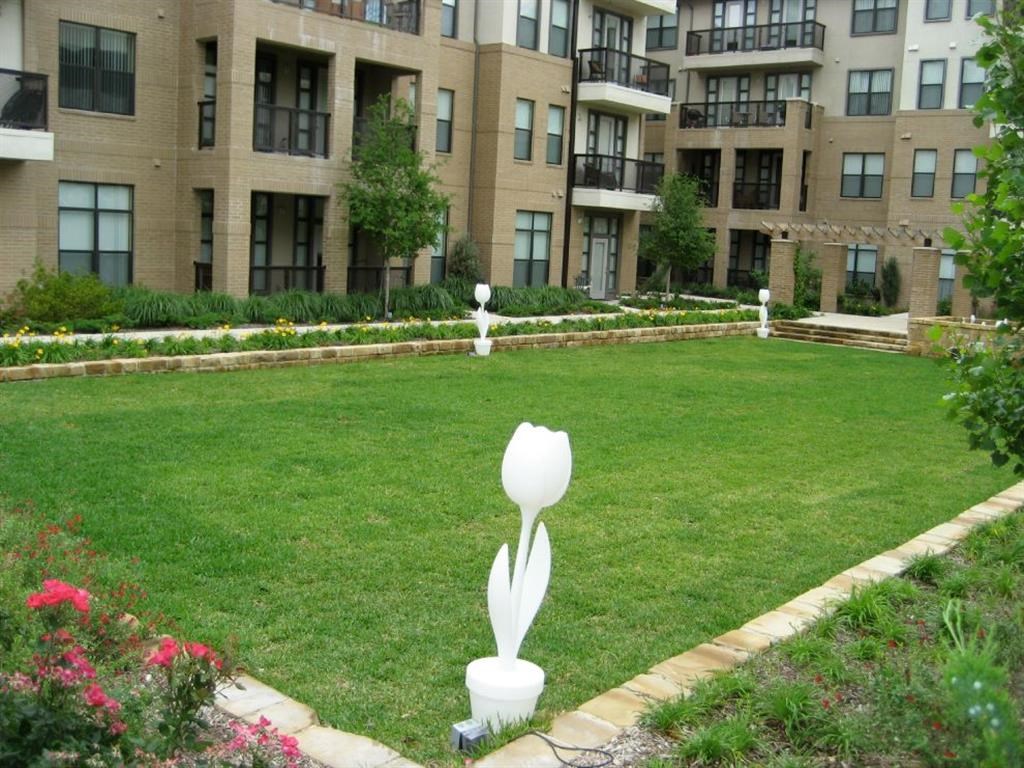 a lawn with a white flower in front of an apartment building