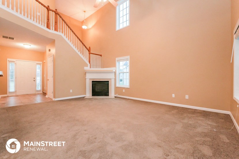 a carpeted living room with a fireplace and a staircase