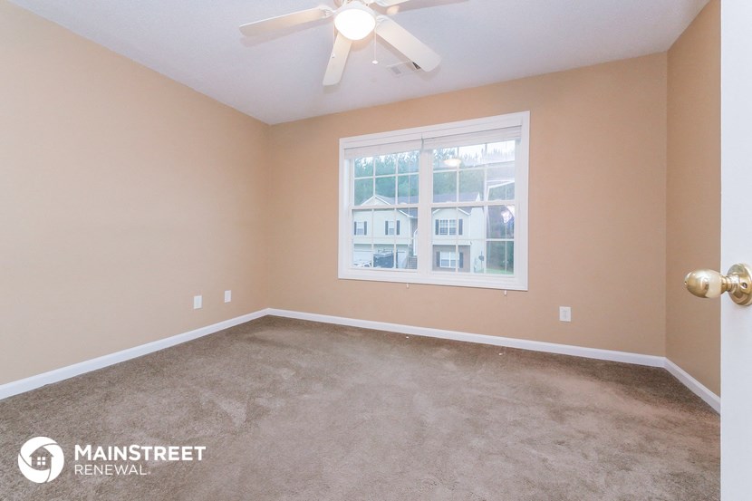 the master bedroom has a large window and carpeted flooring