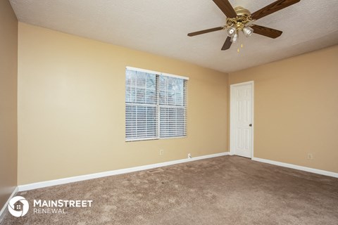 the spacious living room has carpet and a ceiling fan