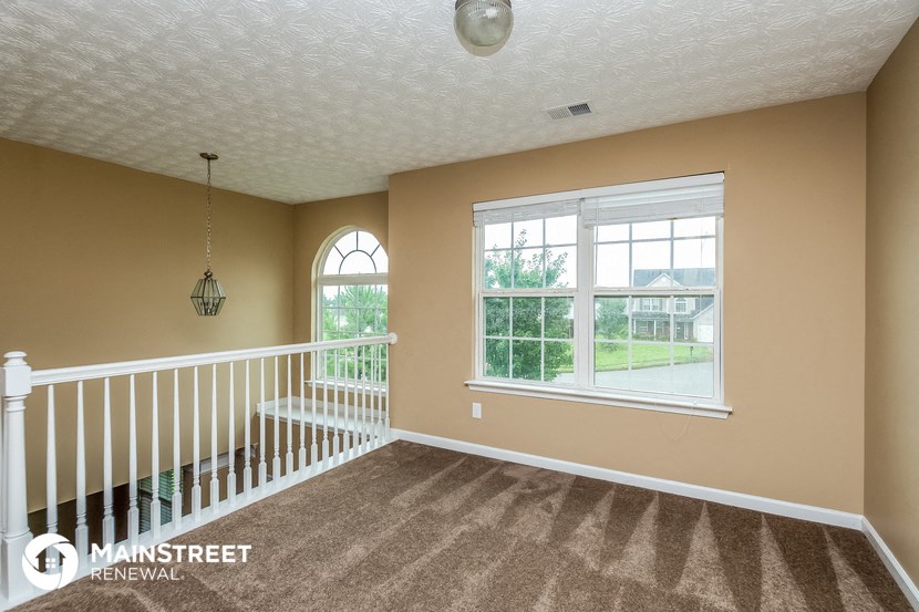 a living room with a staircase and a large window
