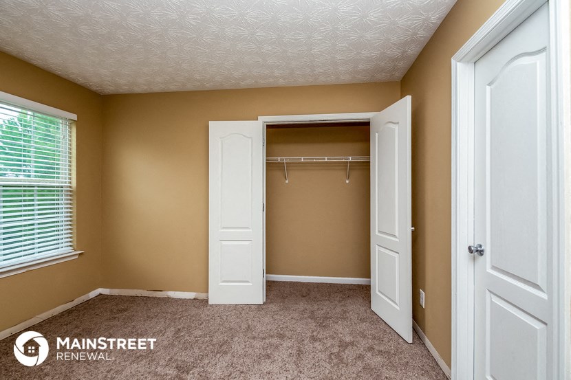 an empty bedroom with a closet and a white closet door and a window
