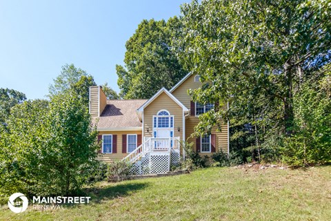 a yellow house with a lawn and trees