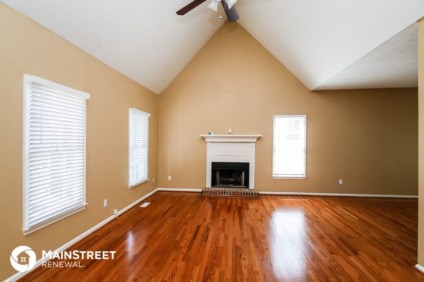 the living room with wood floors and a fireplace