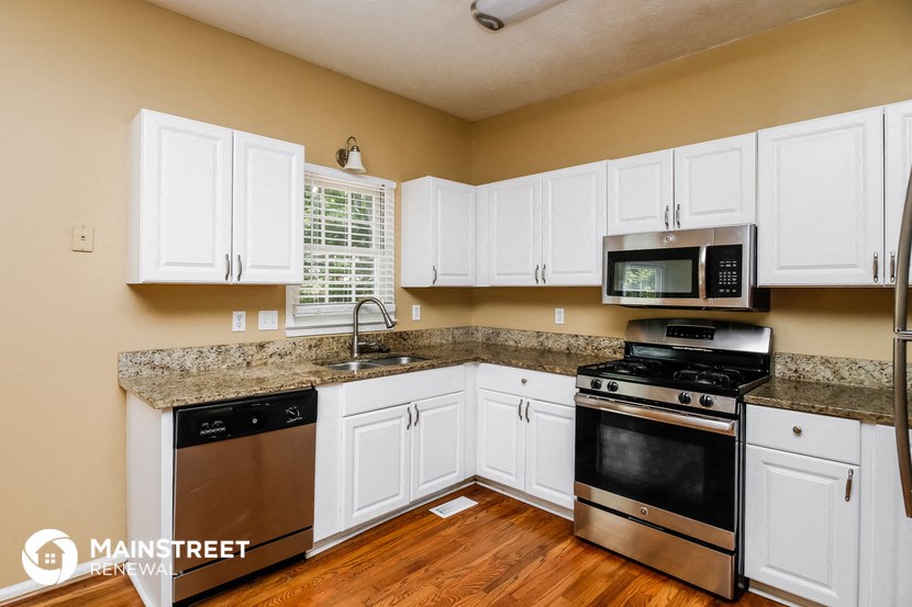 a kitchen with white cabinets and stainless steel appliances and granite counter tops
