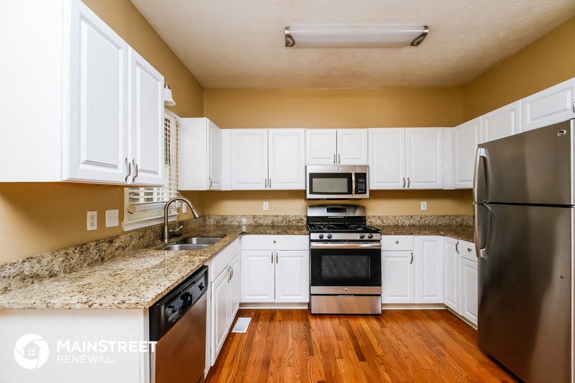 a kitchen with white cabinets and granite counter tops and stainless steel appliances