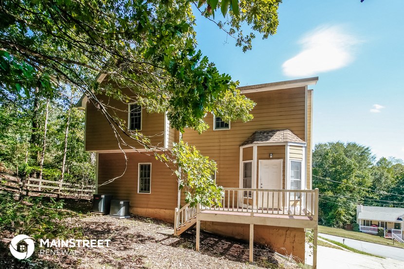 a small house with a porch and a tree