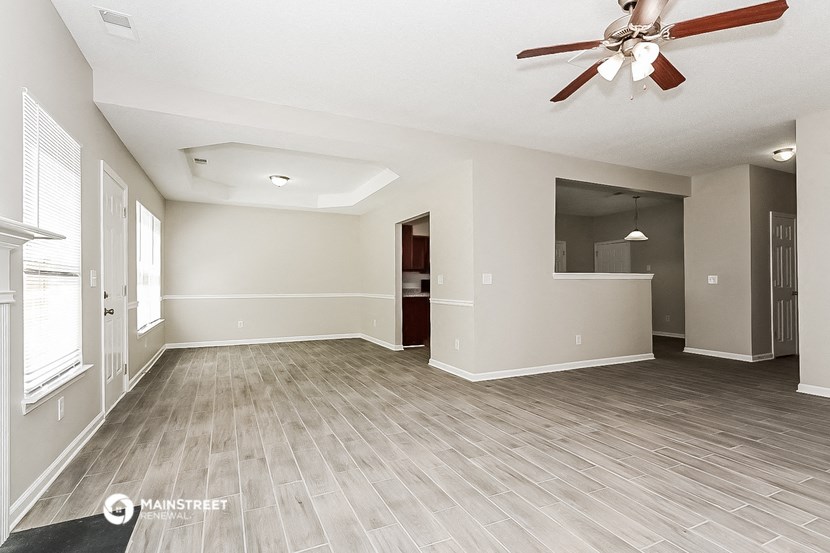 an empty living room with a ceiling fan