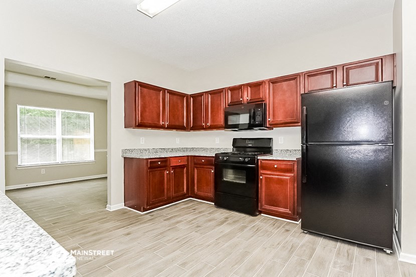 a kitchen with black appliances and wood floors