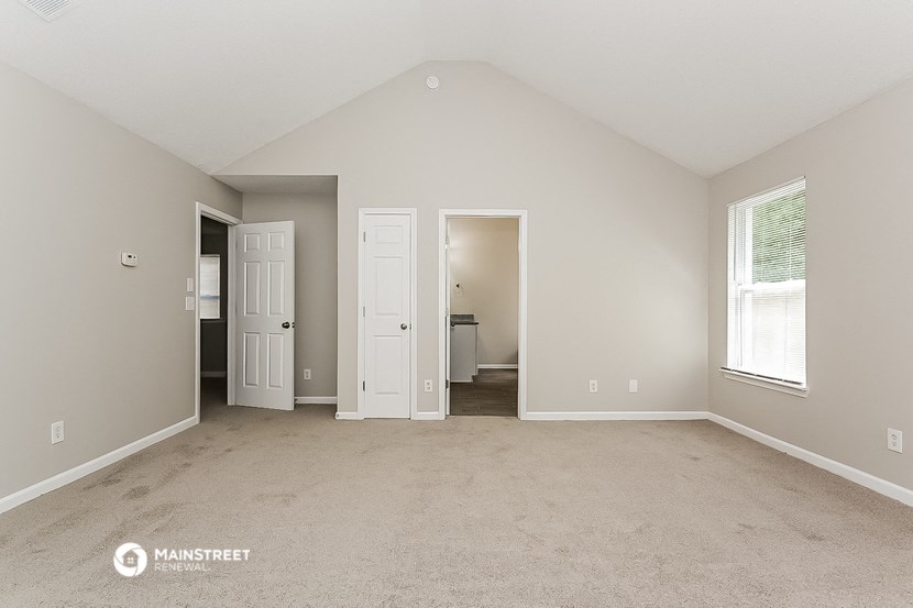 an empty living room with two doors and a window