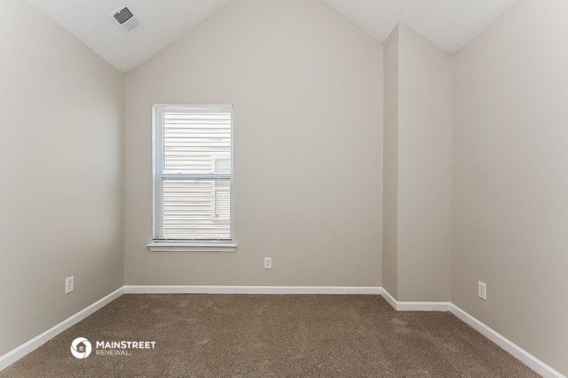 an empty room with a window and carpet