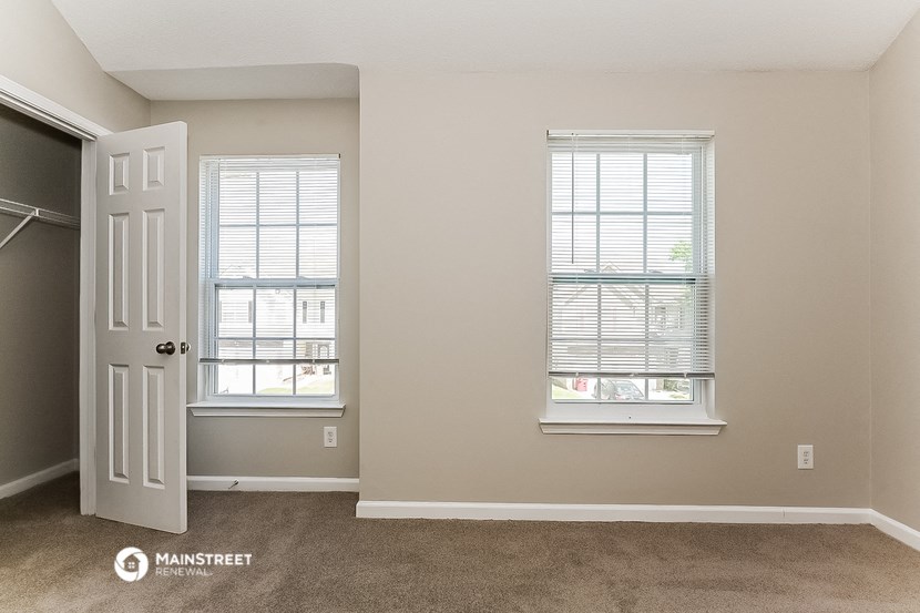 an empty room with a door and two windows