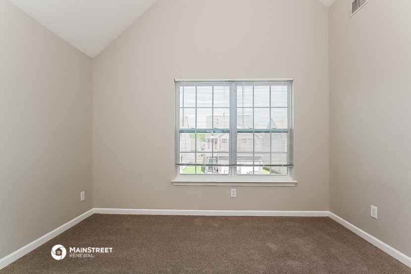 an empty room with a window and carpet