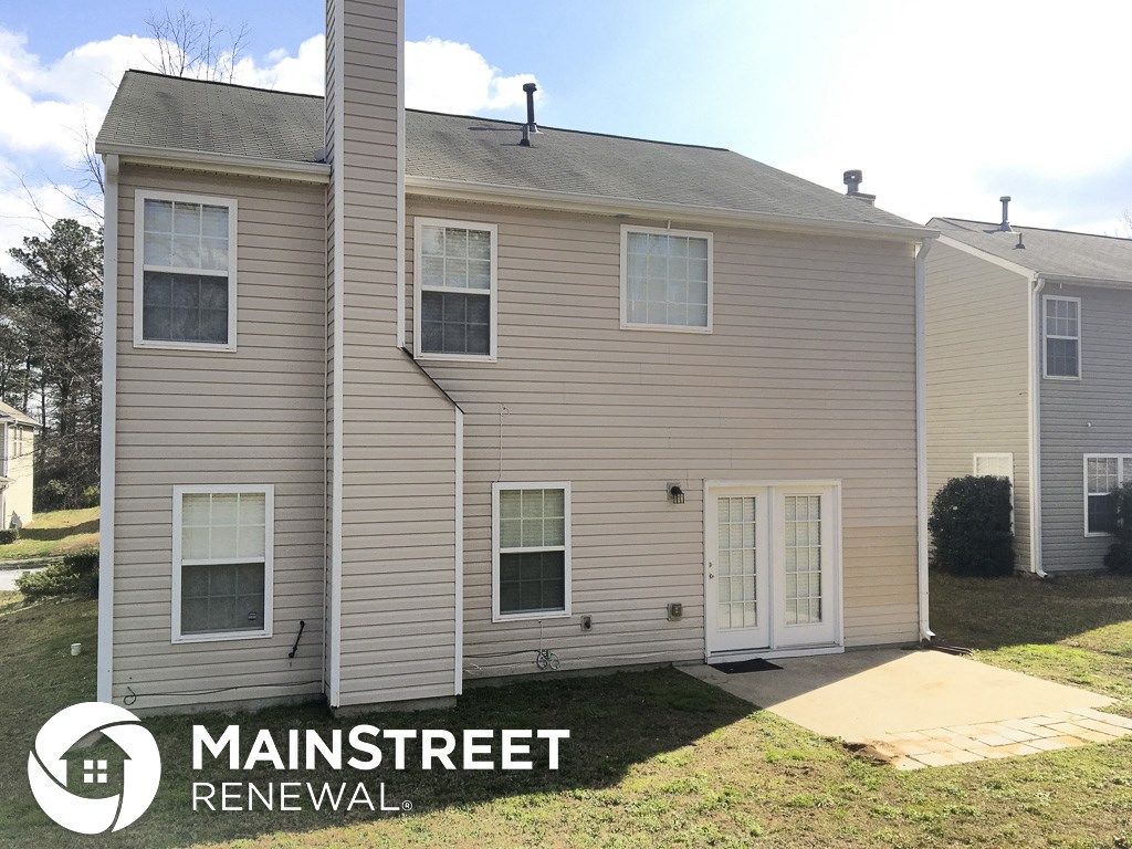 a tan house with white siding and a white door