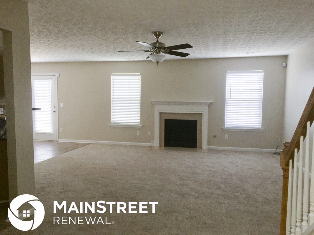 an empty living room with a ceiling fan and a fireplace