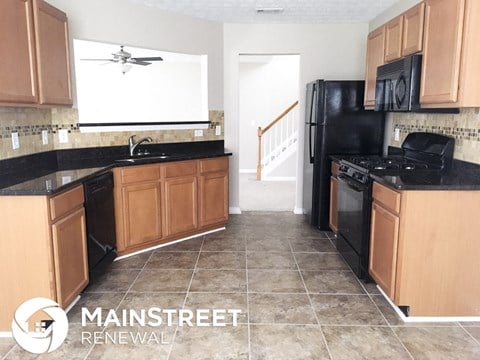 an empty kitchen with black appliances and wooden cabinets