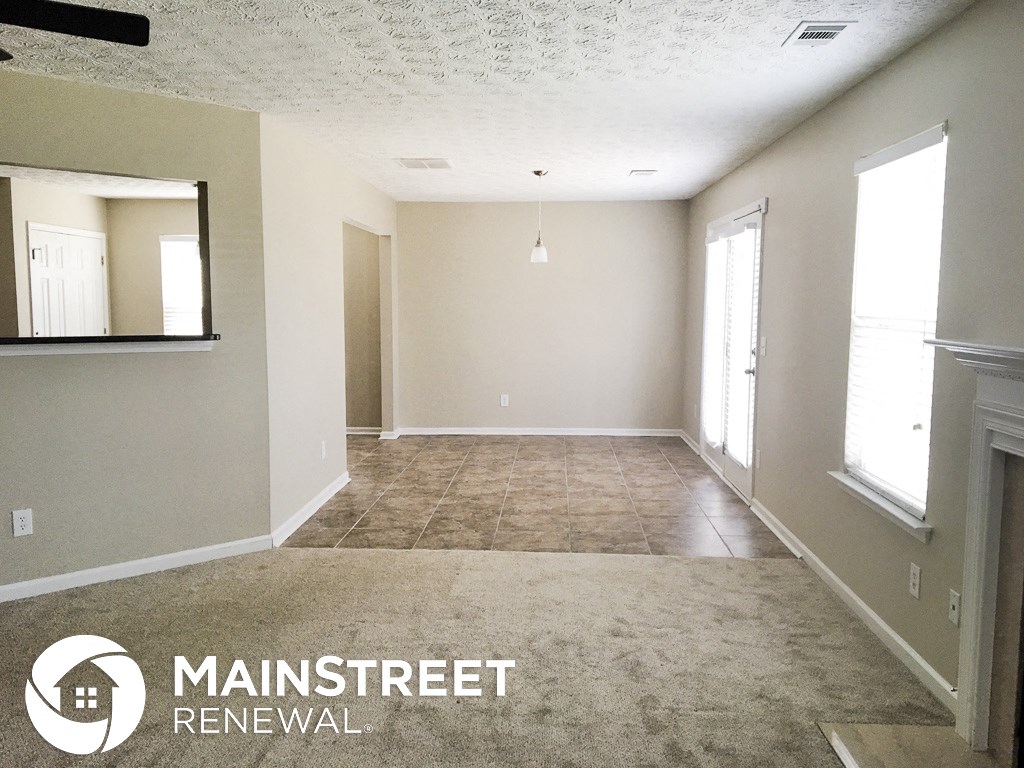 an empty living room with a carpeted floor and a fireplace