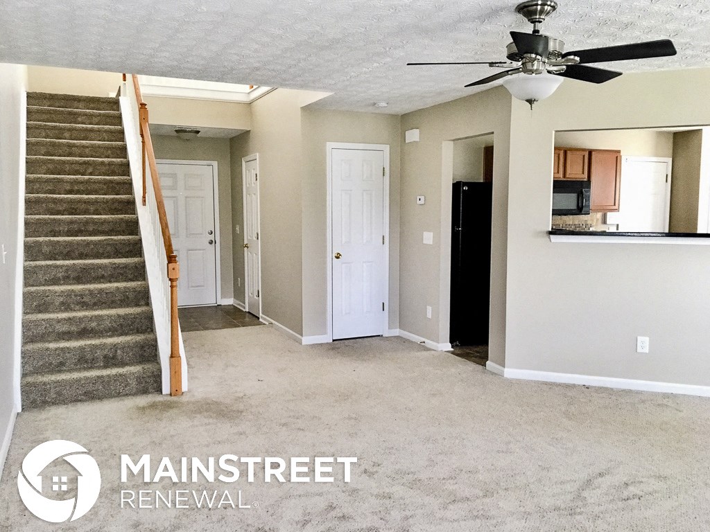 an empty living room with a staircase and a ceiling fan