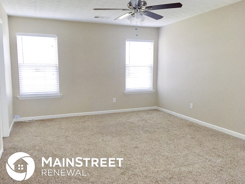 an empty room with a ceiling fan and two windows