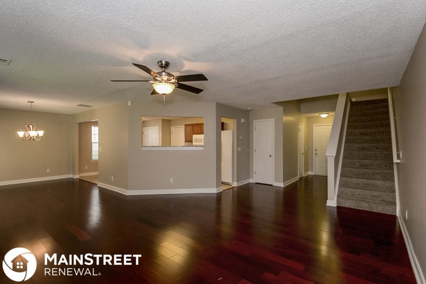 an empty living room with wood floors and a ceiling fan