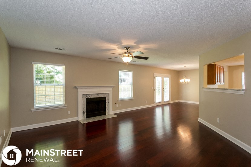 an empty living room with a fireplace and a ceiling fan