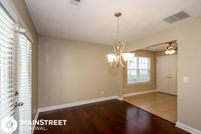 the dining room and living room of an empty house with a door and window