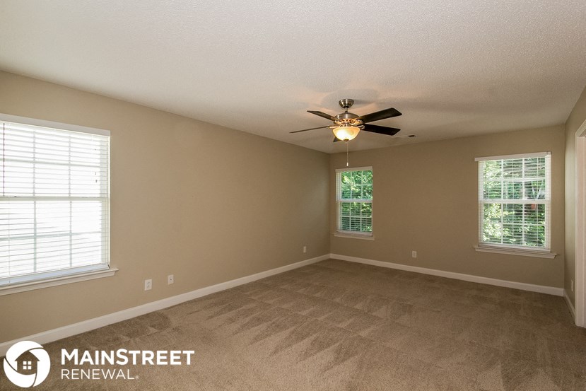 an empty living room with a ceiling fan and a window