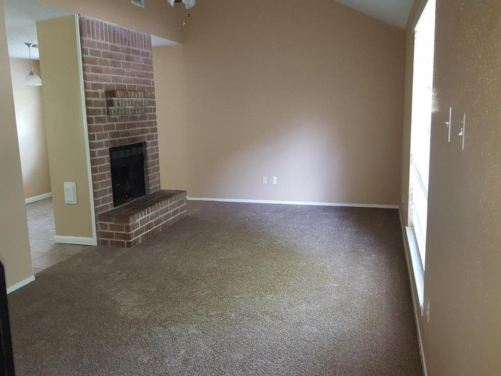 an empty living room with a brick fireplace