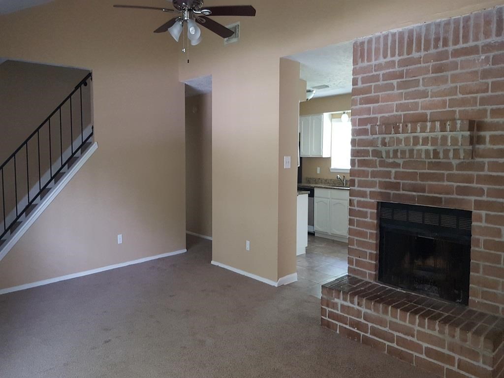 a living room with a brick fireplace and a ceiling fan