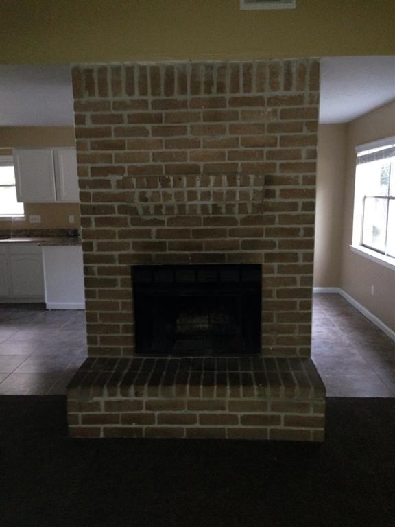 an empty living room with a brick fireplace