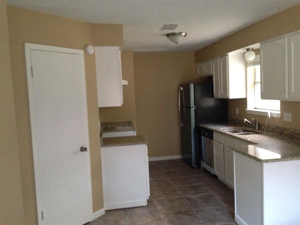 a kitchen with white cabinets and a black refrigerator