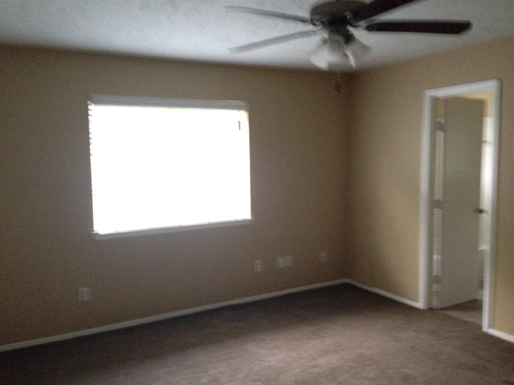 an empty room with a ceiling fan and a window