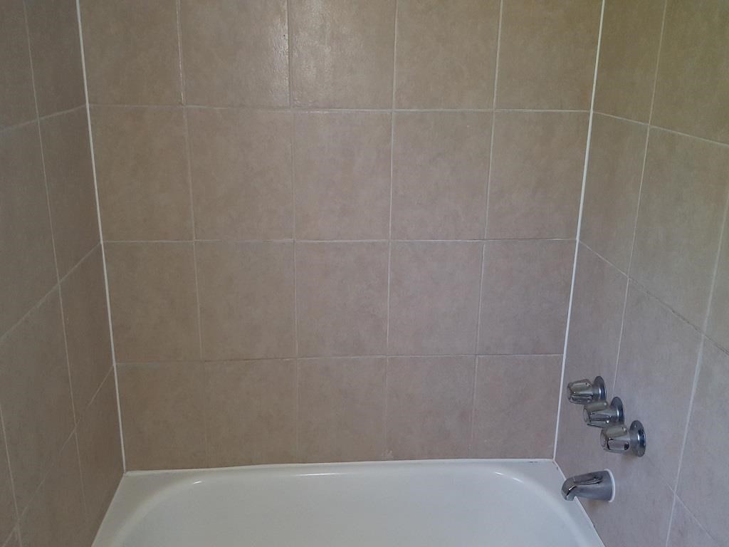 a white bath tub in a bathroom with tiled walls