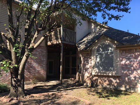 a brick house with a balcony and a tree