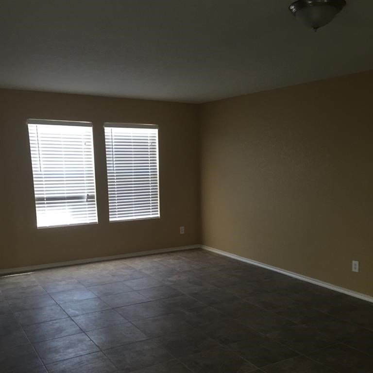 an empty living room with two windows and a tiled floor