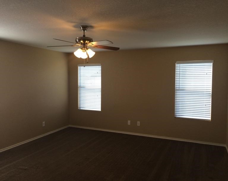 a living room with a ceiling fan and two windows